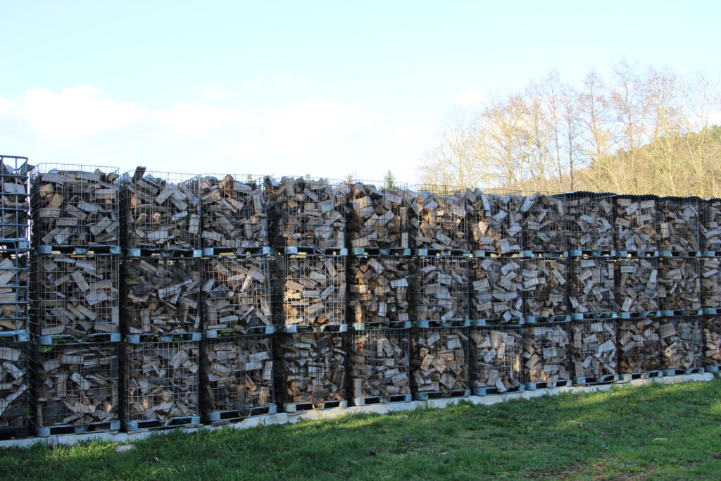 Reihe gefüllter Gitterboxen mit trocknendem Brennholz
